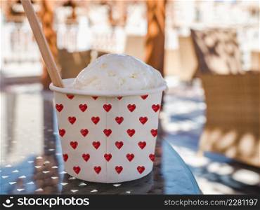 Cup with fragrant ice cream standing on an empty table. Outdoor, close-up. Vacation and travel concept. Cup with fragrant ice cream standing on an empty table