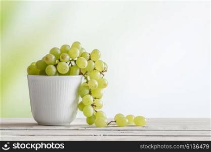Cup with green grapes on a wooden table