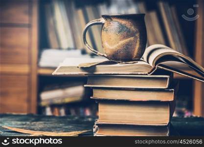 Cup with hot beverage and steam on a stack of books in the library, side view