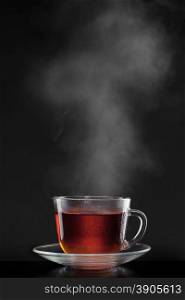 cup with hot tea and steam on black