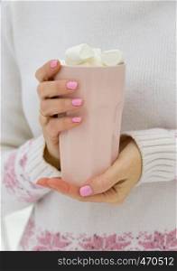 cup with marshmallows in female hands, christmas