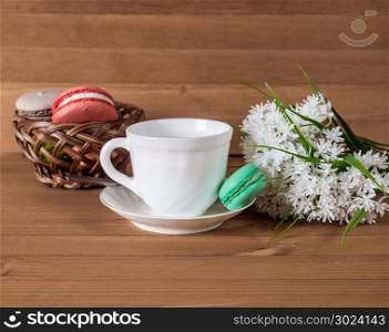 Cup with tea, cakes on the table and white flowers on the background