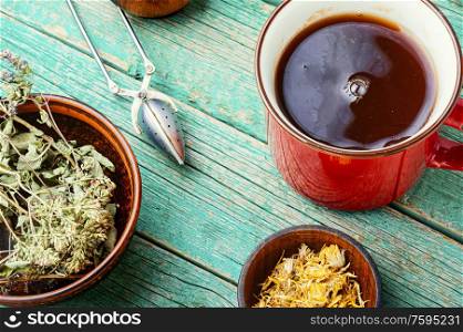 Cup with tea from medicinal herbs on a wooden background. Brewed tasty herbal tea