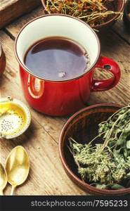 Cup with tea from medicinal herbs on a wooden background. Tea on healing herbs.