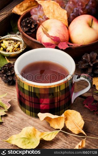 Cup with tea on an autumn background of fallen leaves, apples and grapes.Autumn still life. Autumn still life with tea cups