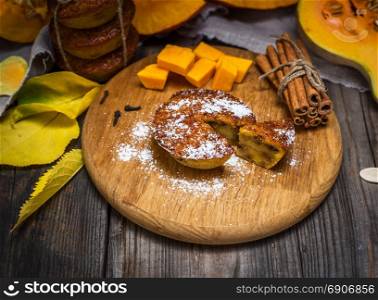 cupcake from a pumpkin on a wooden board, behind fresh pieces of a pumpkin, top view