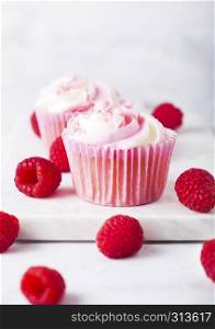 Cupcake muffin with raspberry cream dessert on marble background with freshraspberry
