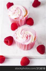 Cupcake muffin with raspberry cream dessert on marble background with freshraspberry