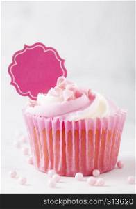 Cupcake muffin with raspberry cream dessert on marble background with pink candies