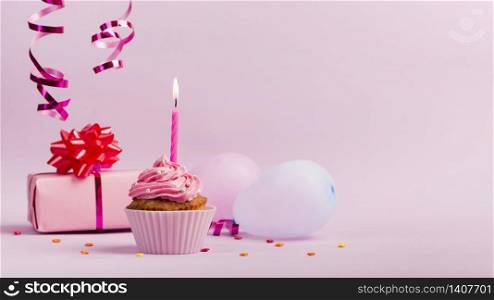 cupcake with happy birthday candles against pink backdrop
