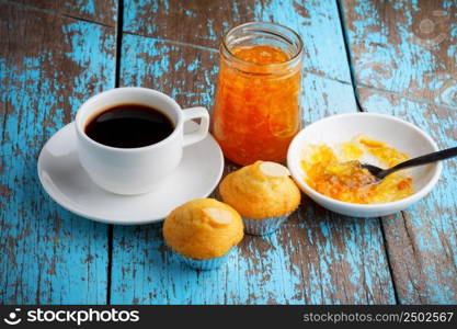 Cupcake with jam and coffee on old wooden table