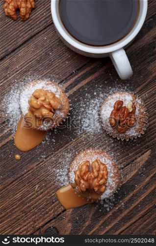 Cupcake with nuts and caramel on old wooden table