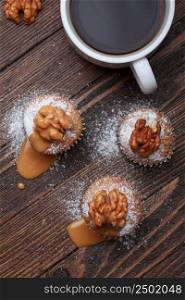 Cupcake with nuts and caramel on old wooden table