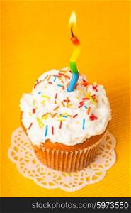 Cupcake with one burning candle on yellow napkin. Cupcake with candle