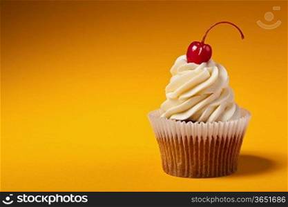 cupcake with red cherry isolated on orange background with copyspace