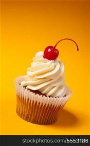cupcake with red cherry isolated on orange background with copyspace