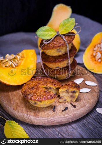 cupcakes from a pumpkin on a wooden board, behind fresh pieces of a pumpkin