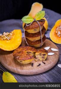 cupcakes from a pumpkin on a wooden board, behind fresh pieces of a pumpkin