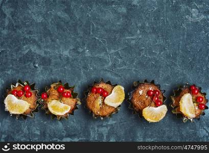 cupcakes in tins ,decorated with berries and slice of tangerine