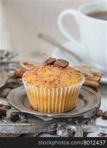 Cupcakes with chocolate shavings and white coffee cup surrounded by coffee beans and a variety of spices with space for text
