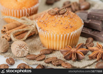 Cupcakes with chocolate shavings surrounded by coffee beans and a variety of spices