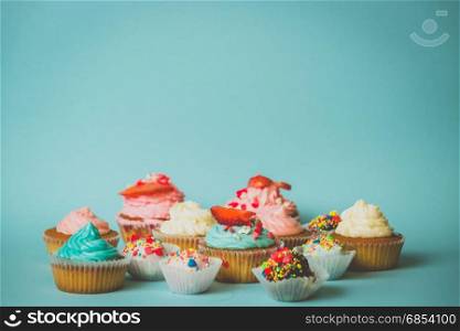 Cupcakes with strawberry and candies with sprinkles on blue background
