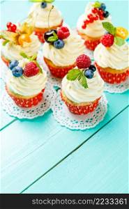 cupcakes with summer berries on blue wooden table. cupcakes with summer berries