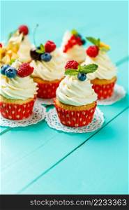 cupcakes with summer berries on blue wooden table. cupcakes with summer berries