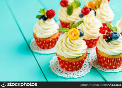 cupcakes with summer berries on blue wooden table. cupcakes with summer berries