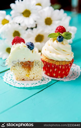 cupcakes with summer berries on blue wooden table. cupcakes with summer berries