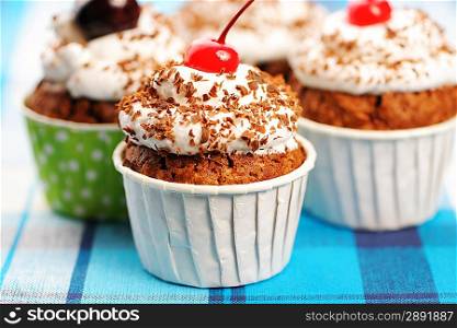 Cupcakes with whipped cream and cherry on a cloth