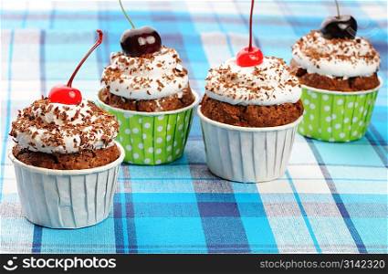 Cupcakes with whipped cream and cherry on a cloth