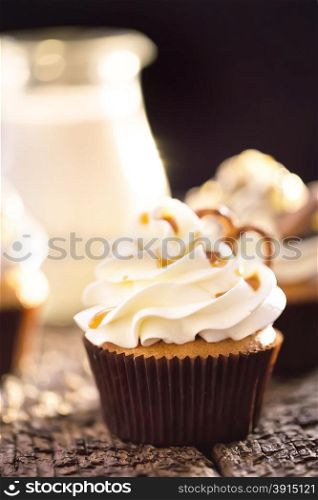 Cupcakes with white cream on a background of a jug of milk
