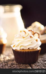 Cupcakes with white cream on a background of a jug of milk