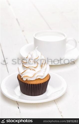 Cupcakes with white cream with cup on white wooden table. Cupcakes with white cream with cup