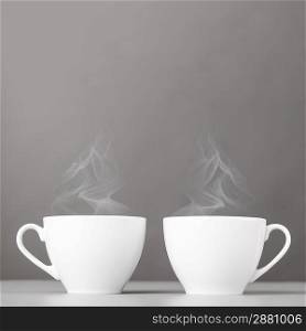 cups of hot coffee on gray background