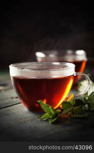 Cups of tea and mint on a wooden background