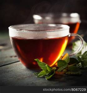 Cups of tea and mint on a wooden background