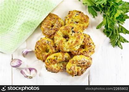 Curd and cheese bagels with garlic and herbs on paper against the background of a wooden board from above