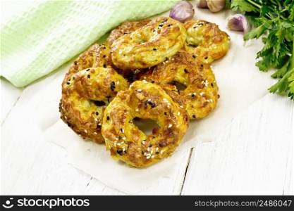 Curd and cheese bagels with garlic and herbs on parchment against the background of a white wooden board