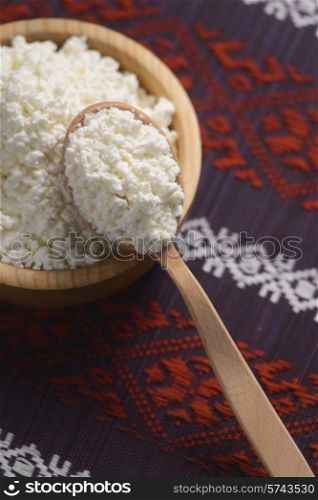 curd in a wooden bowl on the background of the Ukrainian pattern