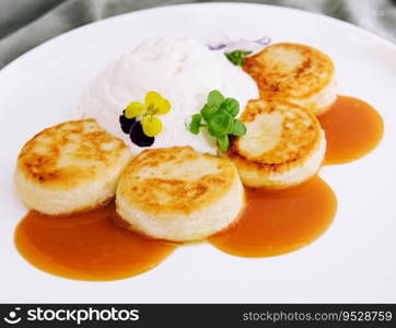 Curd pancakes with sour cream and jam on a white plate