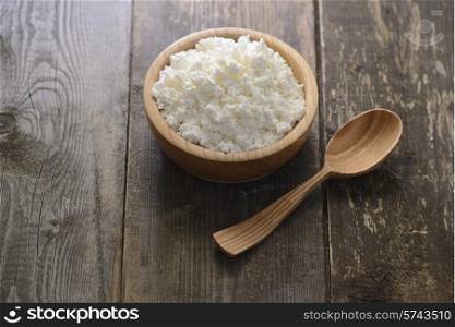 curds in a wooden bowl on a dark wooden background