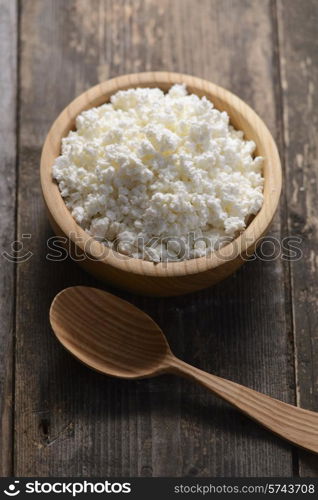 curds in a wooden bowl on a dark wooden background