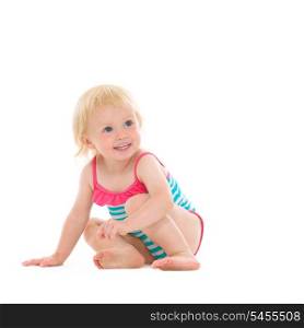Curious baby in swimsuit sitting on floor and looking on copy space