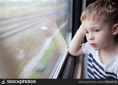 Curious boy looking out the window of a speeding train