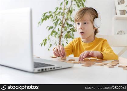 curious little boy using laptop headphones home