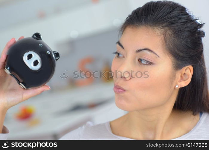 Curious woman holding a piggy bank
