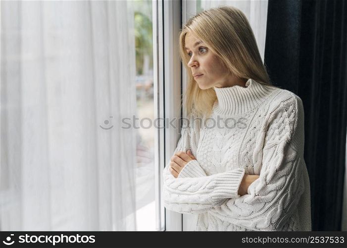 curious woman home during pandemic looking through window