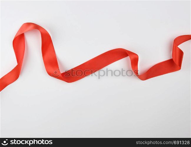 curled red satin ribbon on a white background, close up